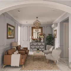 An arched entryway gracefully frames this neoclassical living room, highlighting the design's clean lines and symmetrical layout. The soft, natural light enhances the muted wall tones and plush furniture, creating an airy and sophisticated ambiance.