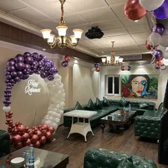 A wide view of a retirement party setup in a lounge, showing how a circular balloon arch and scattered balloon bunches can transform an entire room and create a festive atmosphere.