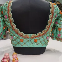 The back of a lovely mint green blouse featuring a lattice pattern with floral details and a scalloped border. The color combination of mint, orange, and pink is fresh and unique.
