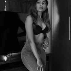 A classic indoor portrait in black and white. The use of natural light from the side creates a gentle yet dramatic mood, highlighting the subject's features and creating a sense of quiet contemplation.