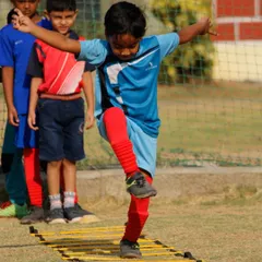 A player demonstrates excellent balance and coordination while navigating the agility ladder during a summer camp session.