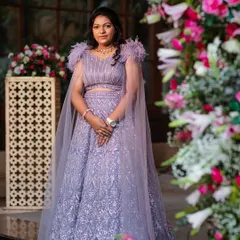 This bride chose a stunning lavender lehenga for her engagement, featuring a modern cut with a flowing cape and feather details on the shoulders. It's a perfect blend of contemporary style and delicate charm.