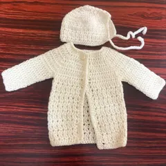 This classic off-white baby set includes a button-up cardigan and a matching bonnet, hand-stitched for a timeless and cozy feel.