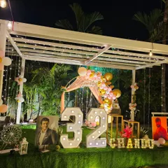 This setup for a 32nd birthday features large marquee numbers, a personalized light-up name, and even framed photos of the birthday person's idol.