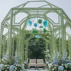 A closer look at the mint green mandap, adorned with a hanging installation of handcrafted paper flowers in shades of blue and green.