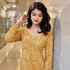 A full-length view of the model in her sparkling gold dress. The makeup complements the outfit perfectly, creating a cohesive and head-turning look that is all about glamour and confidence.