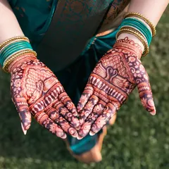The bride's hands form a heart shape, displaying the detailed peacock and floral designs in her henna.