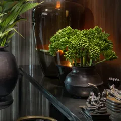 The interplay of shadow and sheen on a console table. We love to style spaces with objects that have a history and a tactile quality, like these antique bronze vessels and fresh greenery, which add life and warmth to the rich wood backdrop.