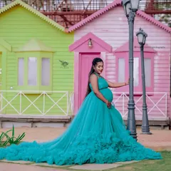 This teal ruffled gown adds a splash of vibrant color to your maternity shoot. The long, flowing skirt creates a beautiful silhouette against the colorful backdrop.