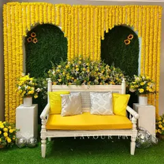 A classic Haldi setup with a modern twist. We created arches made entirely of marigolds against a green backdrop, with a clean white bench and disco balls for a touch of fun.