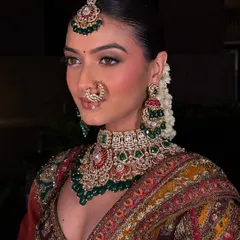 This is the kind of high-quality, professional look you can create with our rental collection. This model is wearing a complete bridal set, including a detailed choker with green and red accents, matching earrings, maang tikka, and nath.