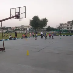 A wide view of a kids' skating session in progress on the multi-sport court. You can see parents watching from the sidelines as the children learn.