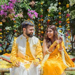 A candid moment from a Haldi ceremony in Goa. The bride and groom are covered in turmeric and flowers, sharing a laugh under the sun. It's a perfect picture of joy and celebration.