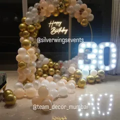 Celebrating a 30th birthday in style. This elegant setup features a circular balloon arch in pastel, white, and gold chrome, a custom neon sign, and large marquee numbers that create a perfect photo opportunity.