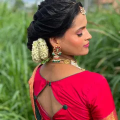Vanitha's complete look, with her hair styled beautifully to complement her bright pink and green saree.