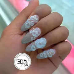 Intricate 3D floral art for a truly special occasion. These stiletto nails feature a sparkling silver glitter base, overlaid with beautifully sculpted white flowers and delicate pearl centers, creating a textured, dimensional masterpiece.