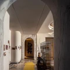 A view through a marble archway in the Palais Royale showflat. The passageway celebrates understated elegance, with artworks punctuating the linear flow and the geometry of the layout softened into fluid, welcoming forms.
