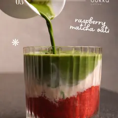 An action shot of matcha being poured into a layered raspberry drink. This dynamic image is visually striking and shows the process of creating a unique beverage. The vibrant colors make it perfect for Instagram.