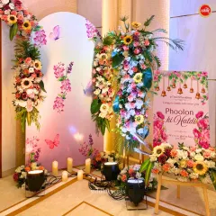 The welcome area for the 'Phoolon ki Haldi', with a custom sign, colorful floral arrangements, and arched panels creating a festive and inviting atmosphere.
