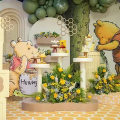 A dessert corner from the Winnie the Pooh baby shower, with "BABY" blocks and a Pooh character cutout next to tiered stands for treats.