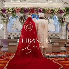 A powerful shot from an Anand Karaj ceremony. The bride's stunning red veil with the 'Ek Onkar' symbol flows behind her as she and the groom stand before the Guru Granth Sahib.