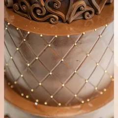 A close-up of the quilted pattern on our luxury chocolate wedding cake. The design is accented with tiny gold pearls, adding a touch of elegance and sophistication to the rich chocolate finish.