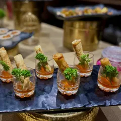Presentation is key for passed appetizers. Here, I serve crispy spring rolls in individual glasses with a sweet chili dipping sauce at the bottom, an elegant and mess-free way for guests to enjoy a classic starter.