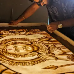 The final touches on a large-scale sand art piece. The light from the lightbox illuminates the sand, giving it a divine glow.