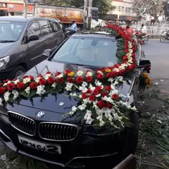 A premium BMW decorated with a garland of red and white flowers. I provide on-location service to decorate any car model, ensuring a royal look for the groom's arrival.