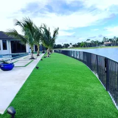 An artificial grass lawn installed next to a pool and lake. My turf is durable and drains quickly, making it a great, mess-free option for waterfront properties.