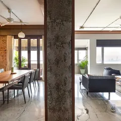 This image captures the essence of our open-plan design philosophy. The living and dining areas of 'The Canvas' apartment flow into one another, separated only by a raw concrete column, creating a unified space that is perfect for both family life and entertaining.