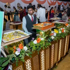 My staff attending to a beautifully decorated salad counter at a wedding. The floral arrangements and lighting enhance the overall presentation of the food.