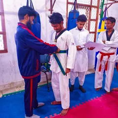 A significant moment as I tie a new green belt on a student, signifying his progress and commitment during a belt distribution ceremony.