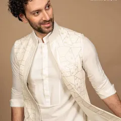 This ivory kurta and Nehru jacket ensemble features a unique geometric embroidery, blending Indian craftsmanship with modern minimalism. It creates a look that’s timeless yet effortlessly contemporary, for the man who believes sophistication lies in the details.
