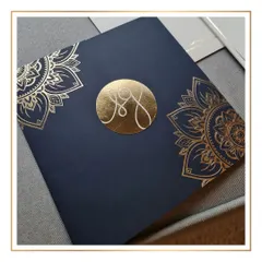 The centerpiece of this design is the custom monogram, foil-stamped in gold on a rich navy blue envelope. The mandala-inspired artwork adds a touch of traditional grandeur to the modern, clean aesthetic.