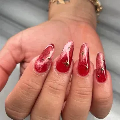 This shot captures the magnetic shimmer of the red cat-eye polish. The light creates a bright streak across the nail, giving it incredible depth and movement.