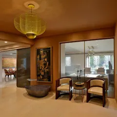 In the foyer, a golden mesh pendant light casts intricate shadows, creating a warm and welcoming entry. This space now flows seamlessly into the main living areas, a stark contrast to its previously enclosed nature.