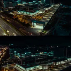 A dramatic night-time aerial shot of the Collins Aerospace building in Bengaluru. Our low-light drone photography highlights the building's modern design and illumination against the city skyline.