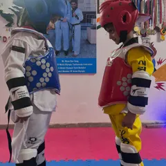 The calm before the storm. Two of our young fighters, fully geared up, face each other with intense focus before their sparring match begins.