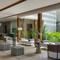 In our Celadon farmhouse project, the formal living area flows effortlessly into a central lounge and an open-air courtyard. This design choice maximizes natural light and fosters a constant connection to the lush greenery, embodying our principle of blurring the lines between inside and out.