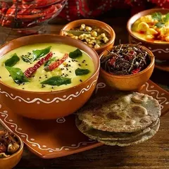 A traditional Rajasthani thali featuring Kadhi, Bajra rotis, and other regional specialties. We use authentic earthenware to enhance the rustic and traditional dining experience.