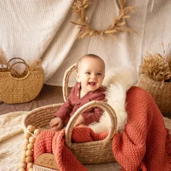 A big, happy laugh from this little one during a boho-themed sitter session. The warm, earthy tones and natural textures create a cozy and joyful vibe.