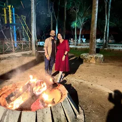 A couple stands by a warm bonfire at our Ramanagara resort, a perfect end to a day of adventure and a great way to spend a cozy evening together.