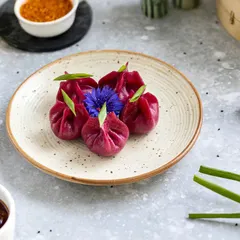 The deep magenta of these beetroot dumplings is the star of this shot. I used edible flowers and fresh greens to complement the colour, creating a visually stunning image for a contemporary Asian restaurant.
