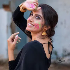 The pure joy of Holi captured in a candid moment. This portrait focuses on the vibrant colors and the model's infectious smile, blending traditional festival fun with a contemporary fashion aesthetic in a black saree.