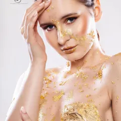 A beauty-focused editorial shot of a model with gold leaf applied to her skin. We excel in creative beauty photography, playing with textures and light to create fine art-style portraits.