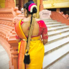 A classic South Indian bridal hairdo featuring a long, thick braid accessory known as 'jade'. This is a quintessential look for a traditional wedding ceremony.
