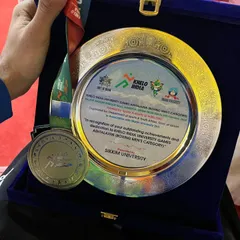 A closer look at the prize. The Gold medal and engraved plaque from the Khelo India University Games, a testament to dedication.