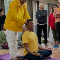 A smile of understanding as a student receives a correction for their seated posture. Proper alignment is the key to a comfortable and deep meditation practice.