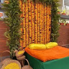 For a pure, traditional Haldi ceremony, we created this backdrop using a dense wall of orange marigold garlands framed with fresh green leaves. We also provide baskets of loose flower petals for the rituals.